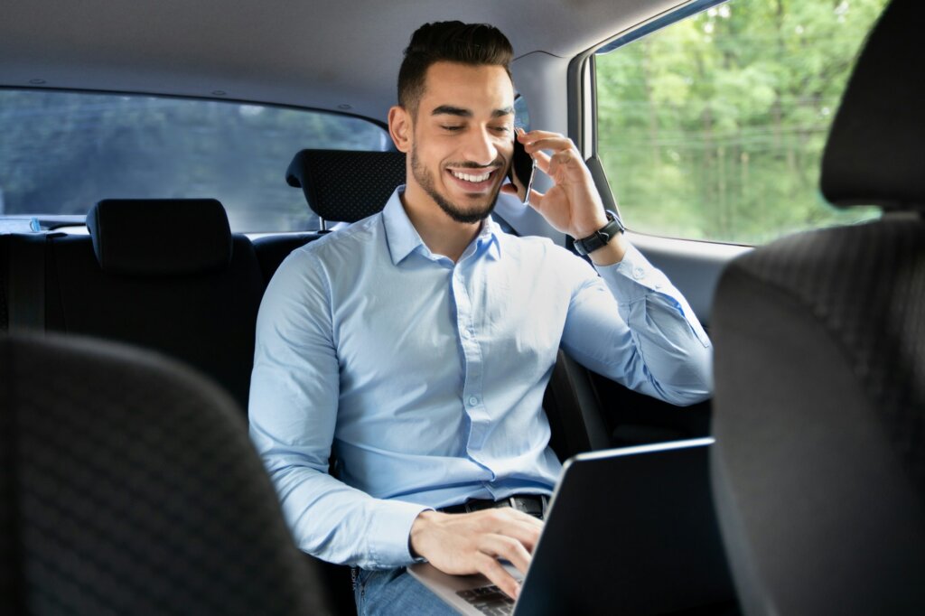 Wealthy businessman working on laptop while going to office